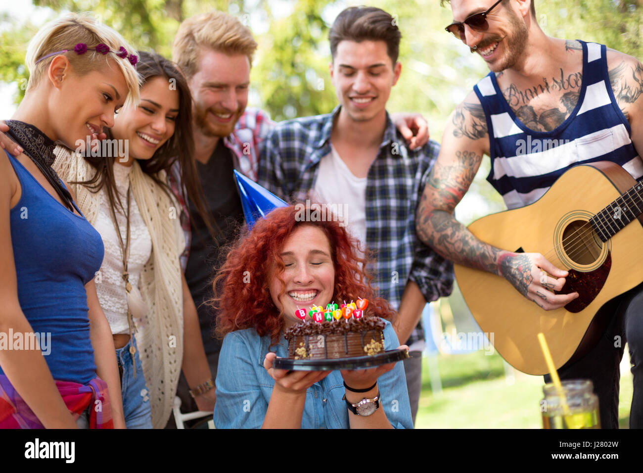 Curly anniversaire fille est très heureux avec ses amis, d'anniversaire gâteau au chocolat sur un anniversaire dans la nature Banque D'Images