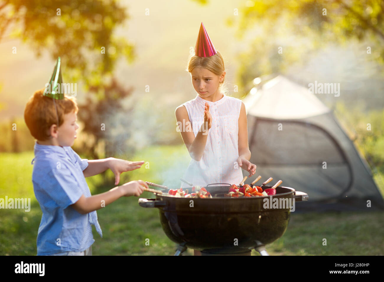 Les enfants ayant une partie de barbecue sur camping Banque D'Images