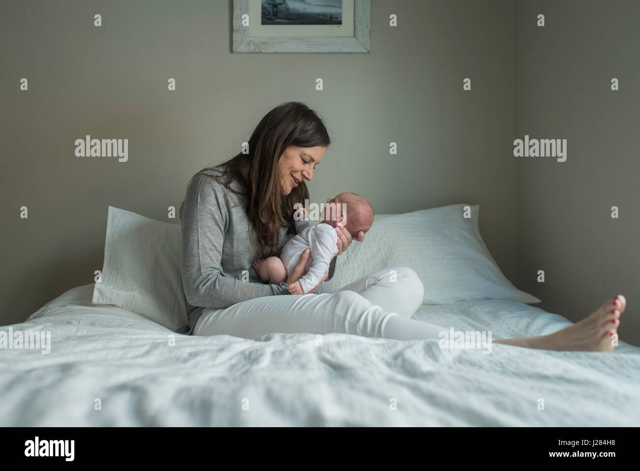 Longueur totale de happy woman Playing with newborn baby boy on bed at home Banque D'Images