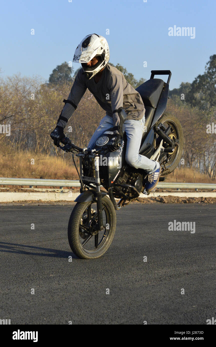 Pilote moto Stunt stoppie faire sur une route locale près de Pune,  Maharashtra Photo Stock - Alamy