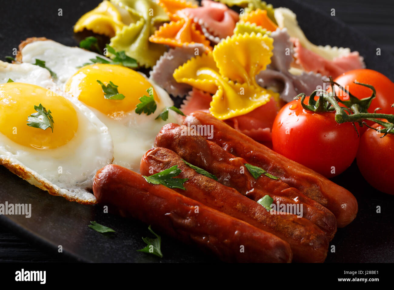 Délicieux petit déjeuner : oeufs frits, saucisses, tomates et pâtes farfalle close-up. L'horizontale Banque D'Images