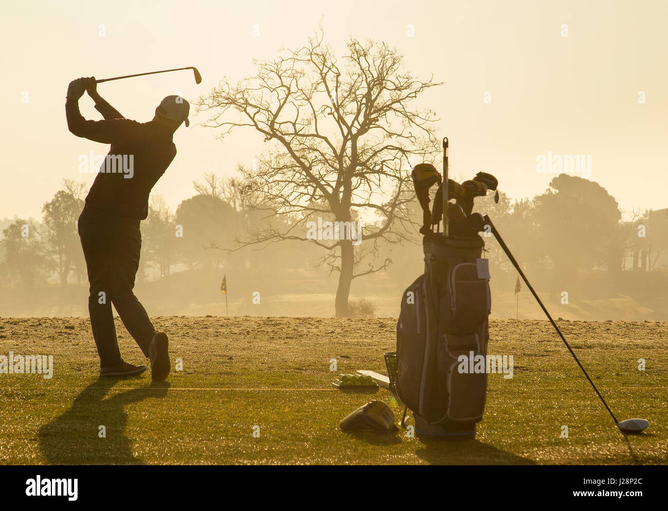 Les golfeurs se balançant clubs de golf de soleil du matin sur la pratique d'entraînement à l'aube. Banque D'Images