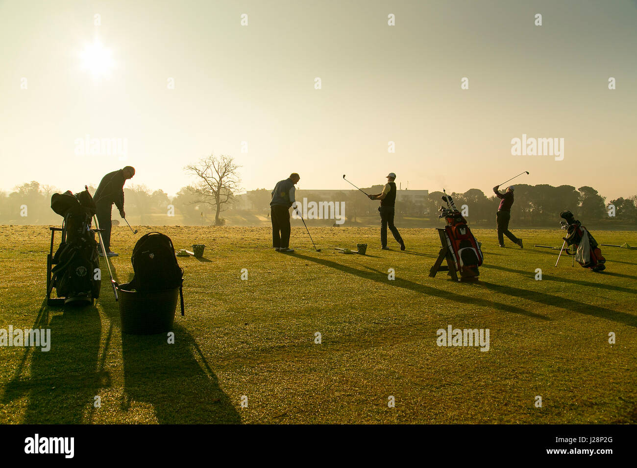 Les golfeurs se balançant clubs de golf de soleil du matin sur la pratique d'entraînement à l'aube. Banque D'Images