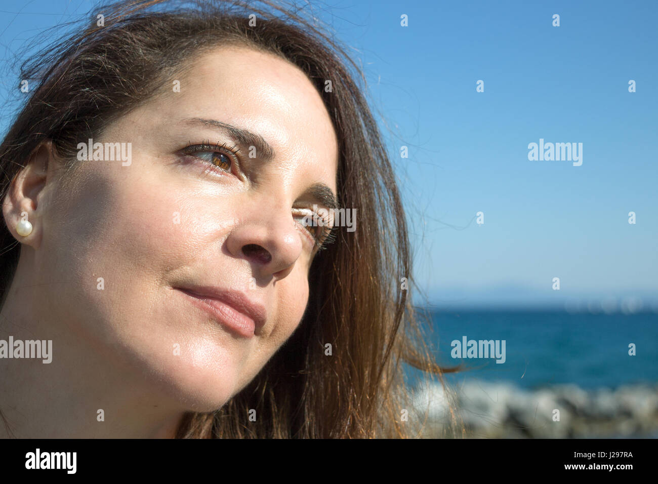 Portrait d'une femme âgée de 45 ans, à la suite, la pensée, les yeux bruns, fond de plage. Banque D'Images
