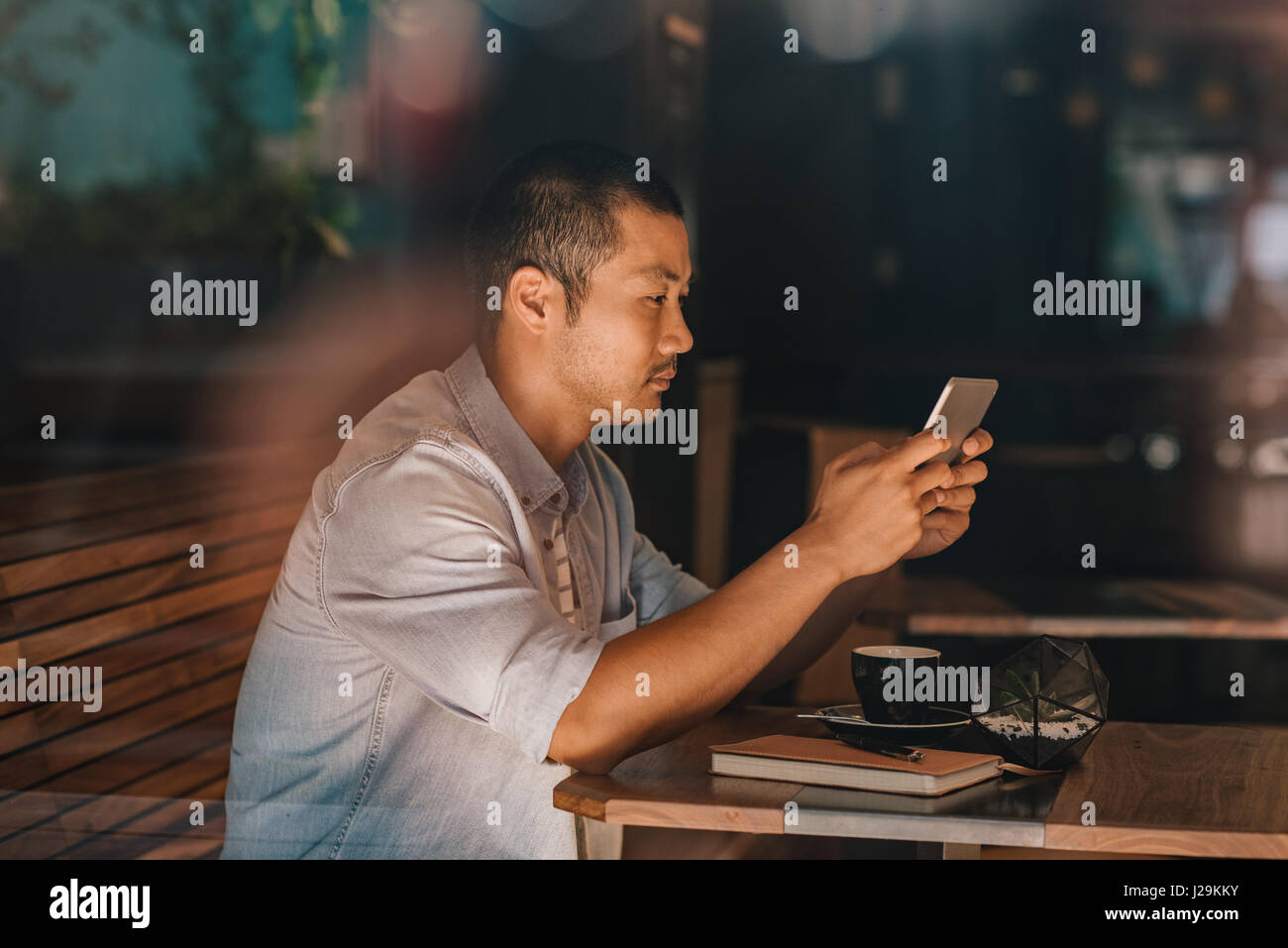 Young Asian man sitting in a cafe la navigation sur internet Banque D'Images