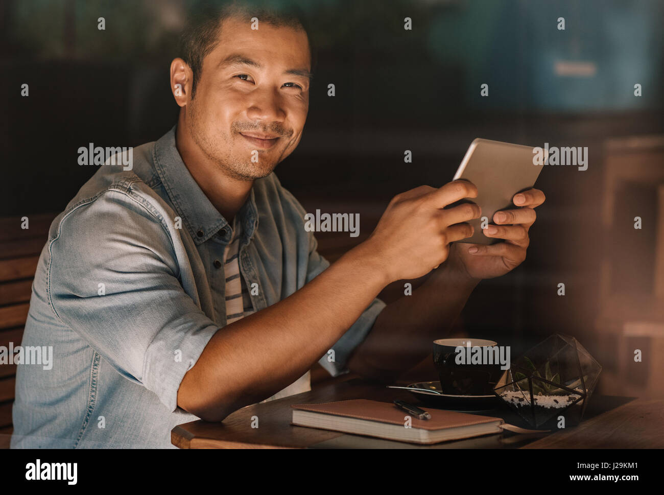 Homme asiatique contenu la navigation en ligne tout en restant assis dans un café Banque D'Images