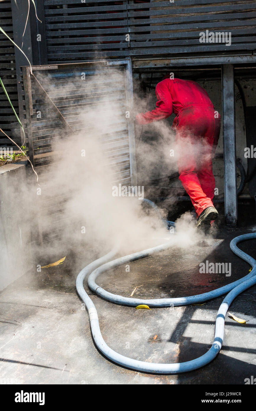 Bel homme dans la fumée. Arrêter le feu avec de l'eau lance Banque D'Images