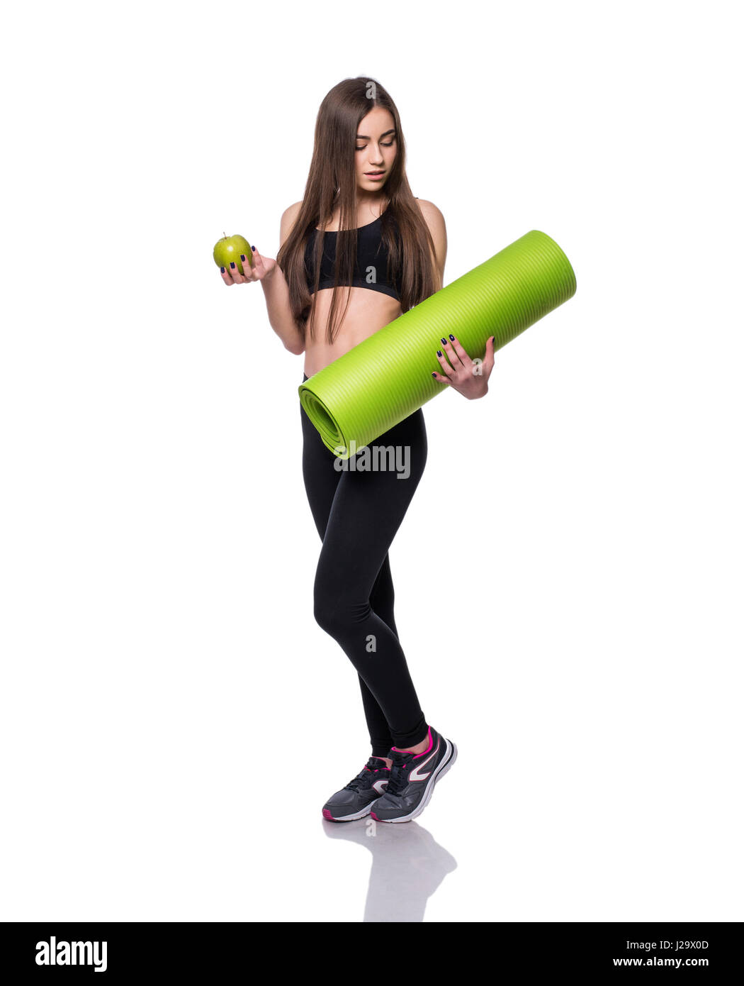 Portrait of smiling young woman holding rolled up exercice tapis de yoga et pomme verte isolée sur fond blanc Banque D'Images