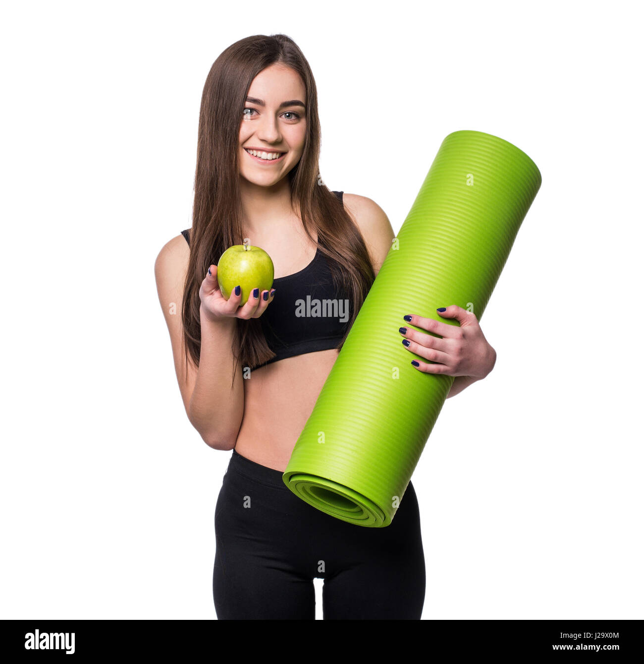 Portrait of smiling young woman holding rolled up exercice tapis de yoga et pomme verte isolée sur fond blanc Banque D'Images