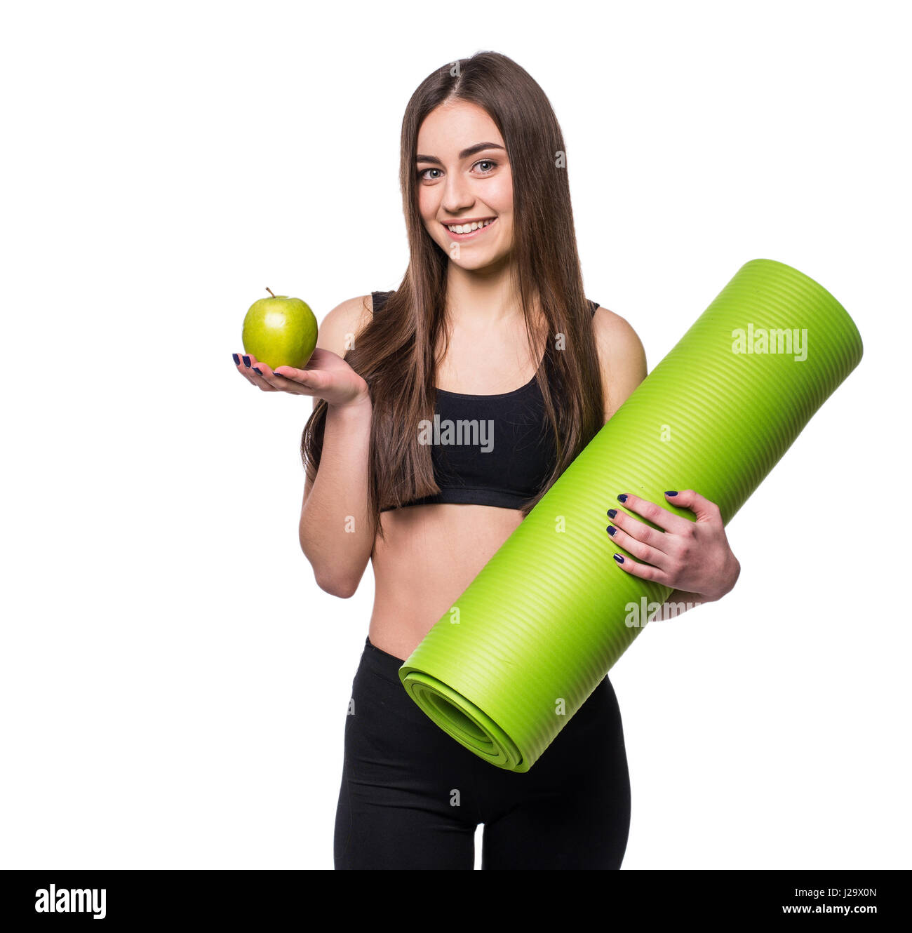 Portrait of smiling young woman holding rolled up exercice tapis de yoga et pomme verte isolée sur fond blanc Banque D'Images