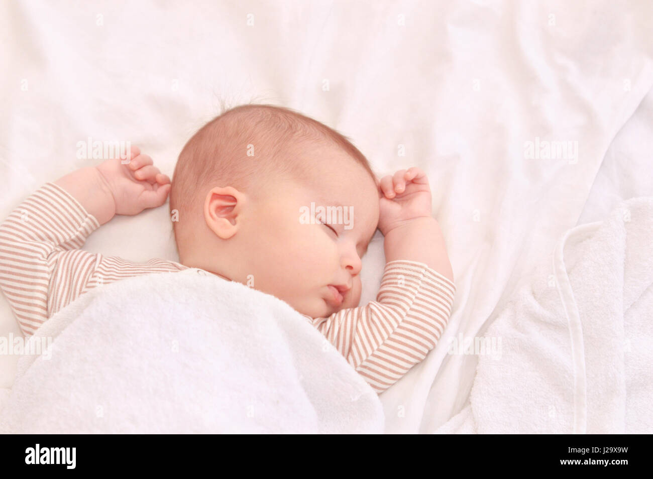 Bébé paisible sur un lit pendant le sommeil dans une salle lumineuse. Le Sommeil du nouveau-né. Les mains derrière la tête. Concept de la maternité heureuse Banque D'Images