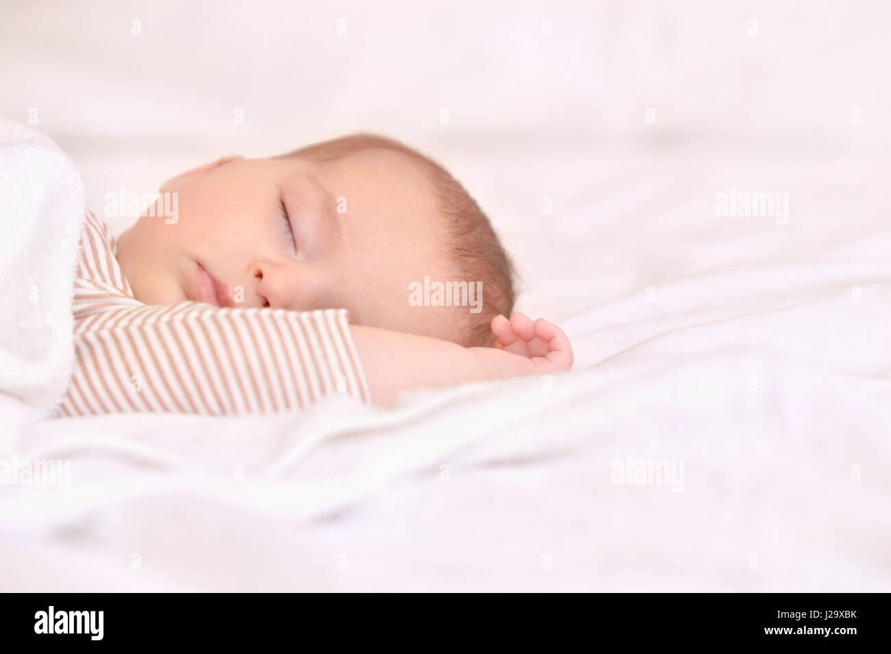 Bébé paisible sur un lit pendant le sommeil dans une salle lumineuse. Le Sommeil du nouveau-né. Les mains derrière la tête. Concept de la maternité heureuse Banque D'Images