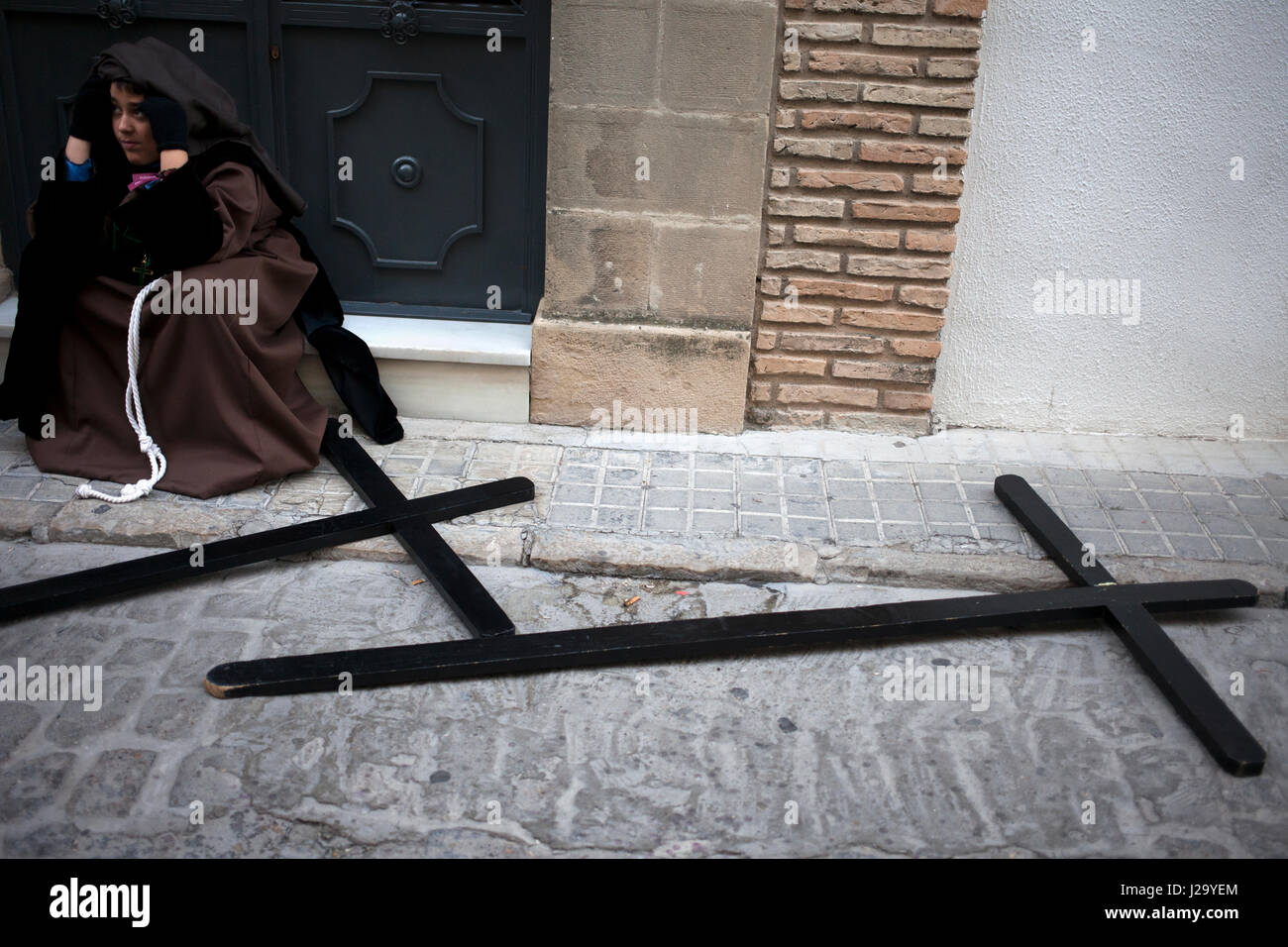 Un jeune pénitent se trouve près de corsés lors de la semaine de Pâques à Baeza, Jaén Province, Andalusia, Spain Banque D'Images