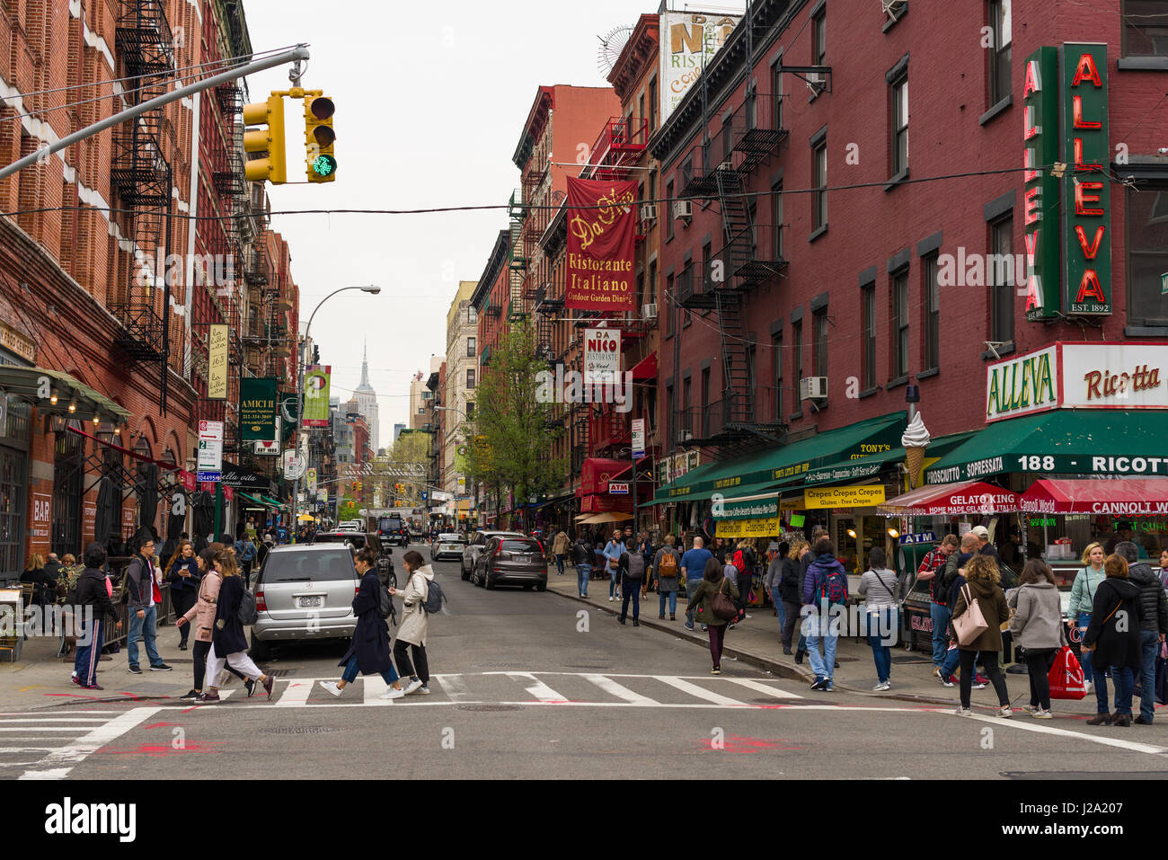 Les gens qui marchent sur la chaussée et traversant une route avec des bâtiments et des restaurants, Little Italy, New York, USA Banque D'Images