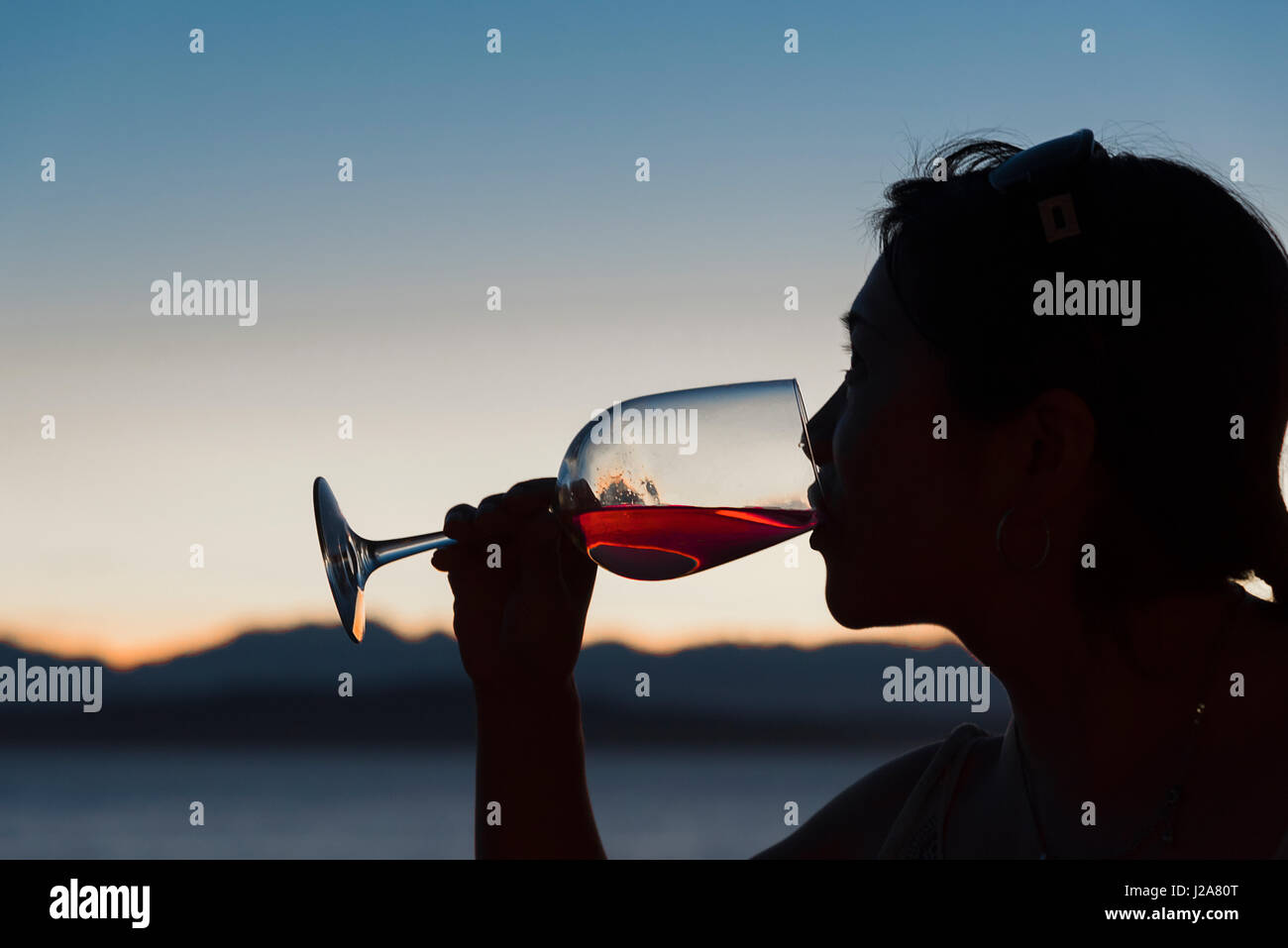 Silhouette Femme buvant du vin rouge par la mer Banque D'Images