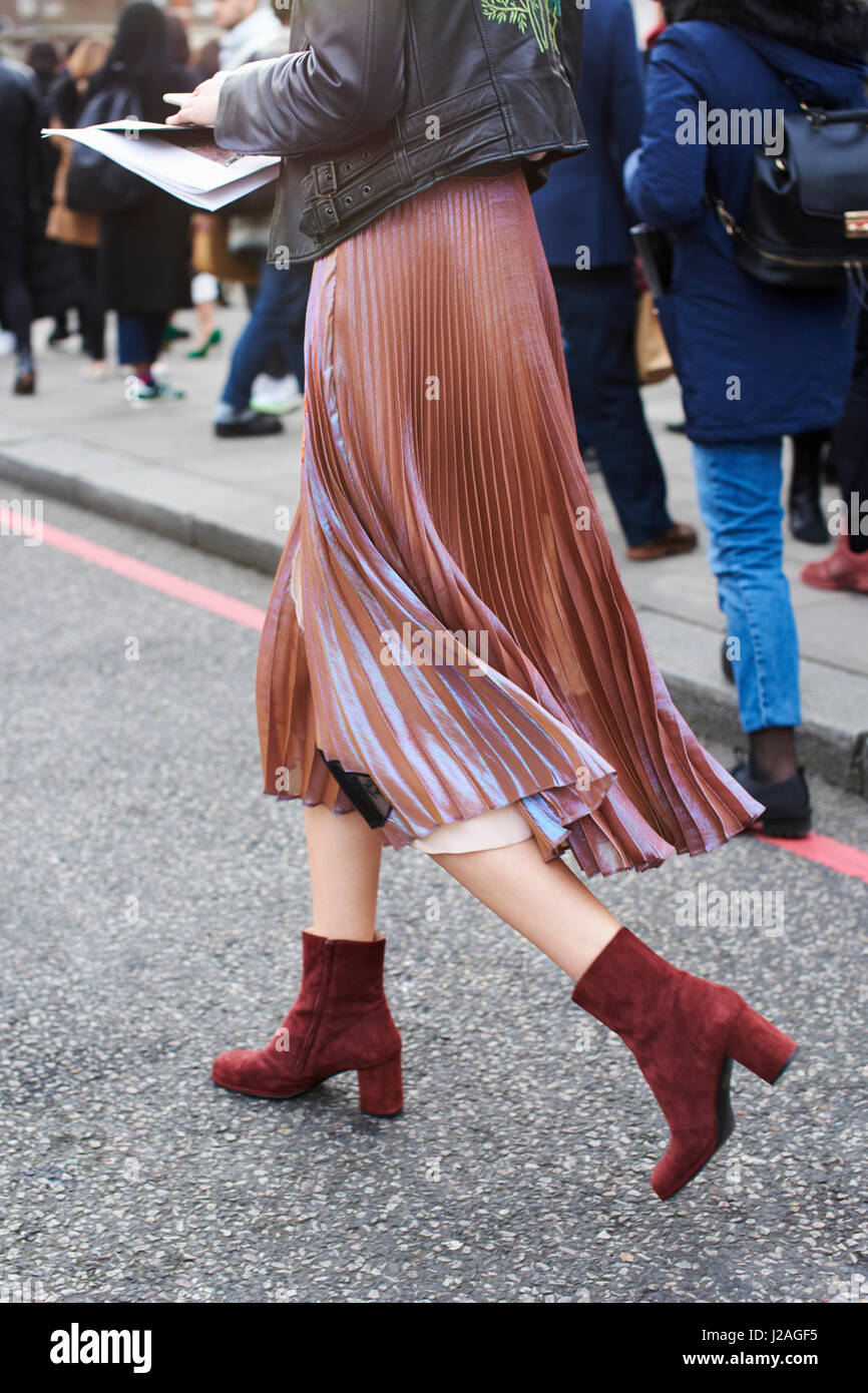 Londres - Février 2017 : young woman wearing mousseline jupe plissée avec passe-partout fini suède marron boots dans la rue lors de la London Fashion Week, vertical, side view Banque D'Images