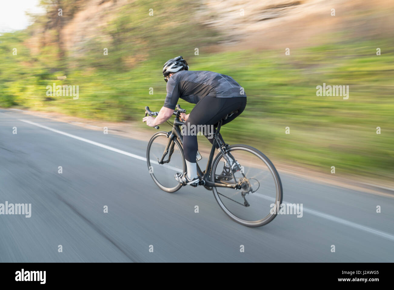 Blurred motion view of man cycling on country road Banque D'Images