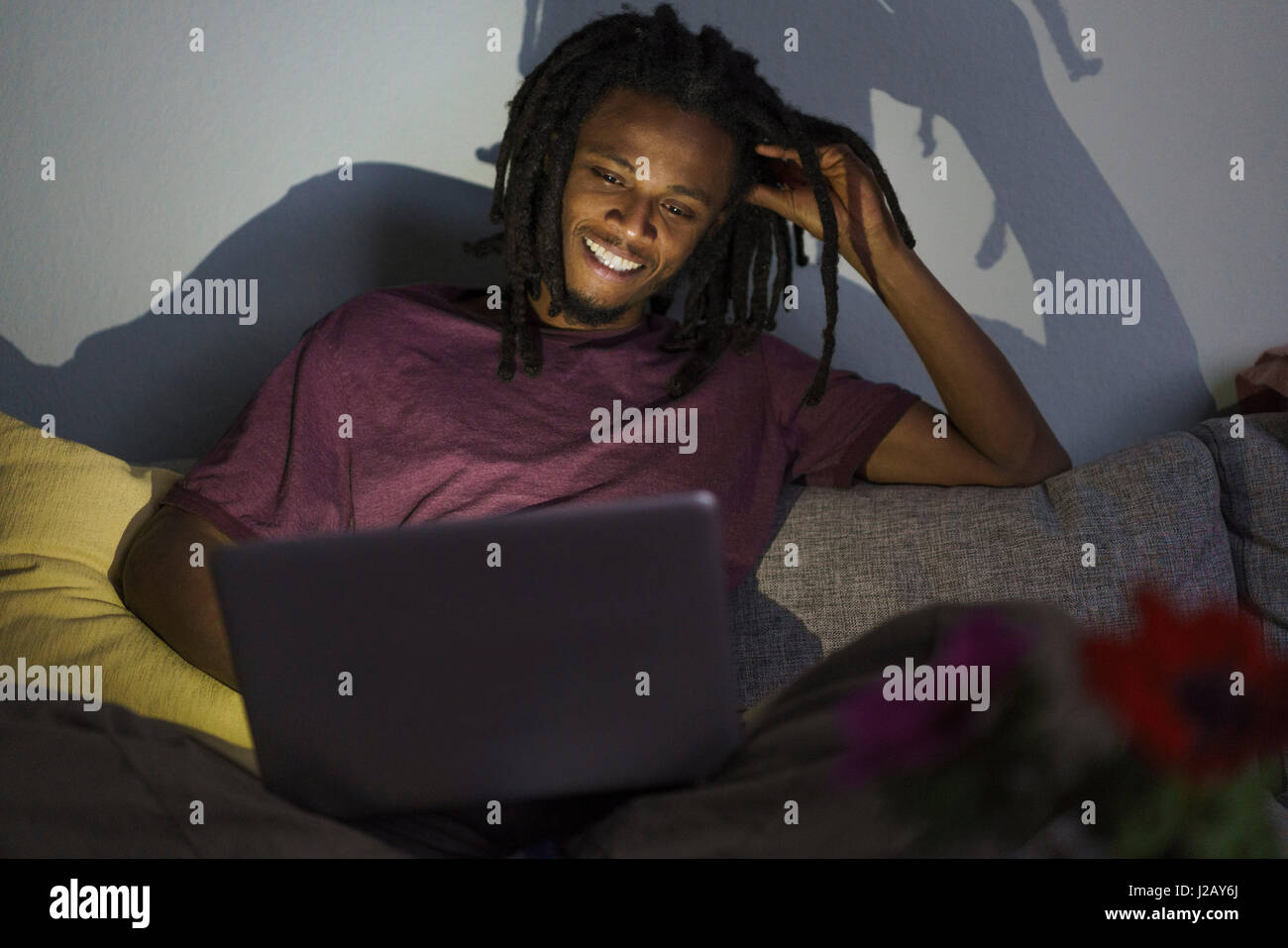 Happy man using laptop while sitting on sofa at home Banque D'Images