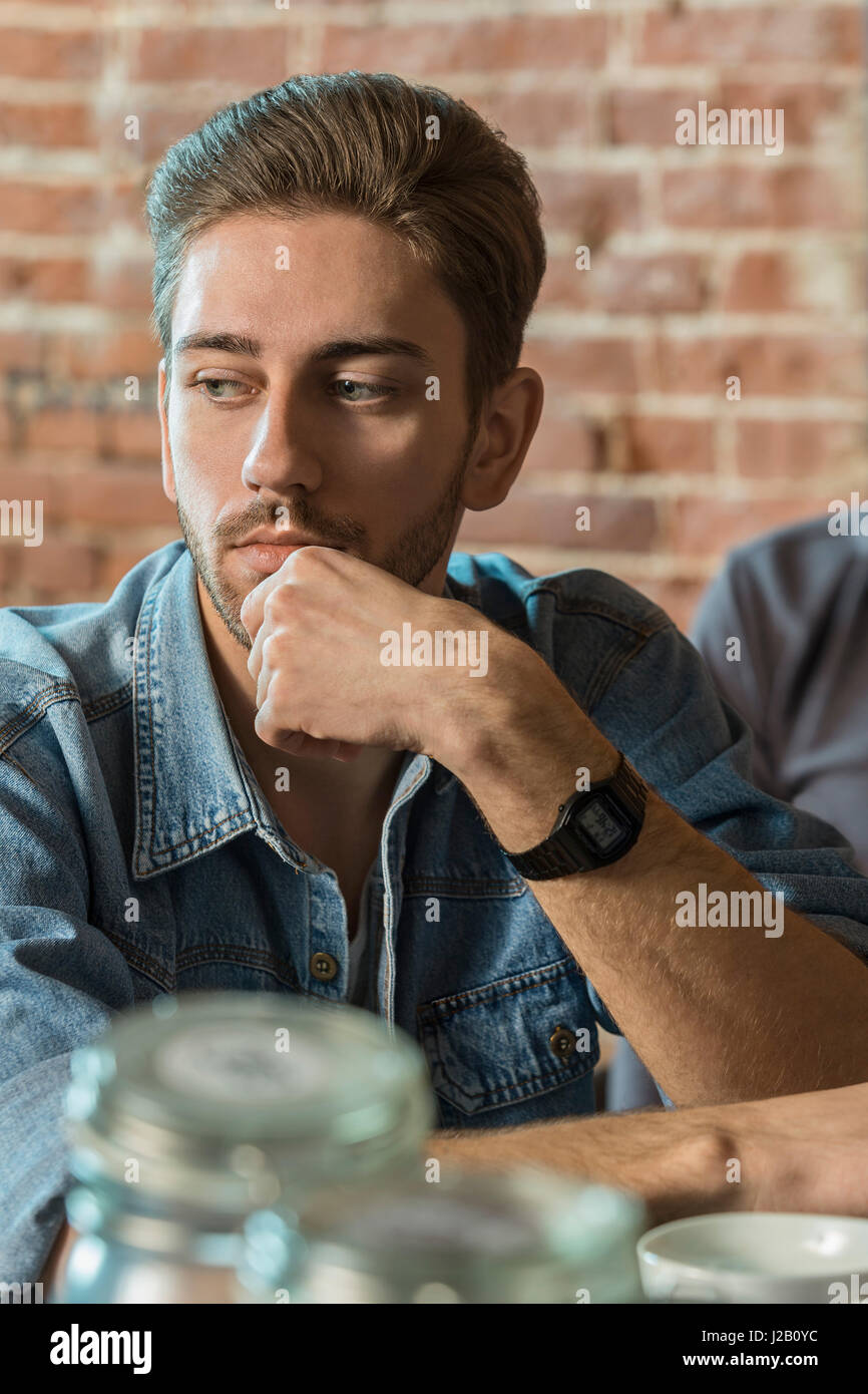 Beau mâle pensif assis à coiffure coiffure Banque D'Images