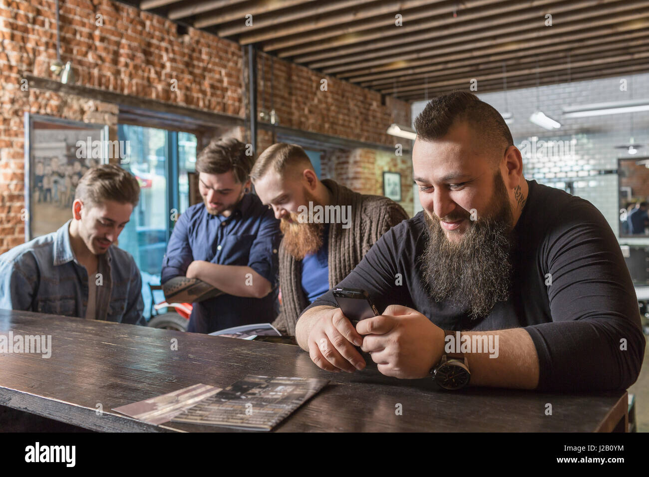 Coiffure masculine à l'aide de mobile avec des collègues au comptoir de barber shop Banque D'Images