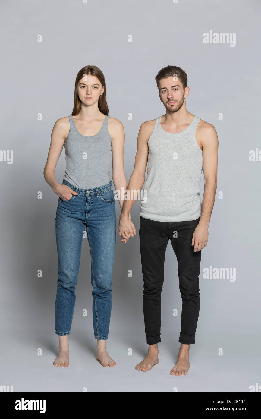 Portrait de couple holding hands while standing against gray background Banque D'Images