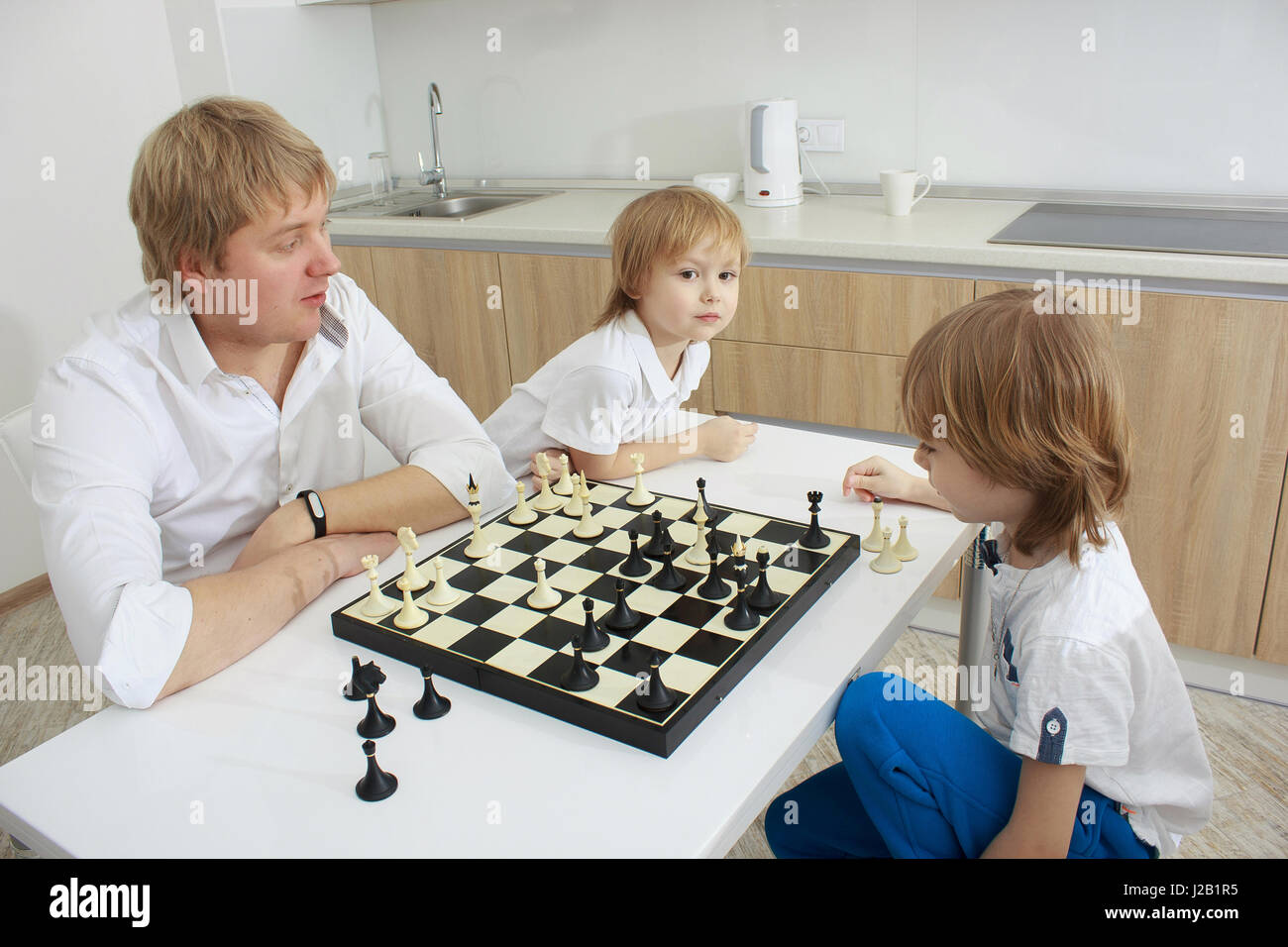 Famille en jouant aux échecs sur une table à la maison Banque D'Images