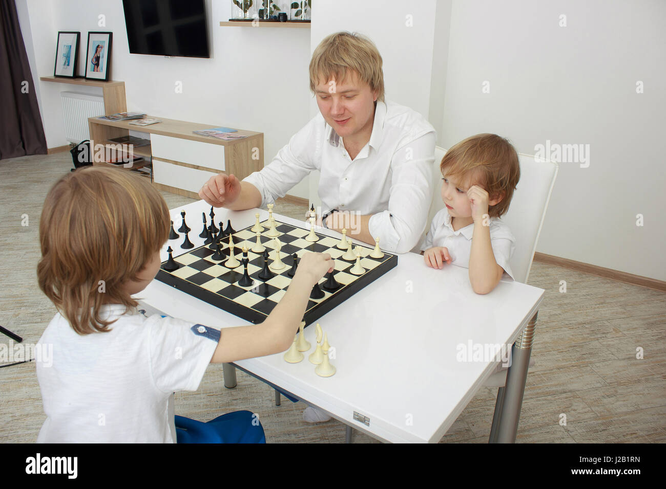 Famille en jouant aux échecs sur une table à la maison Banque D'Images