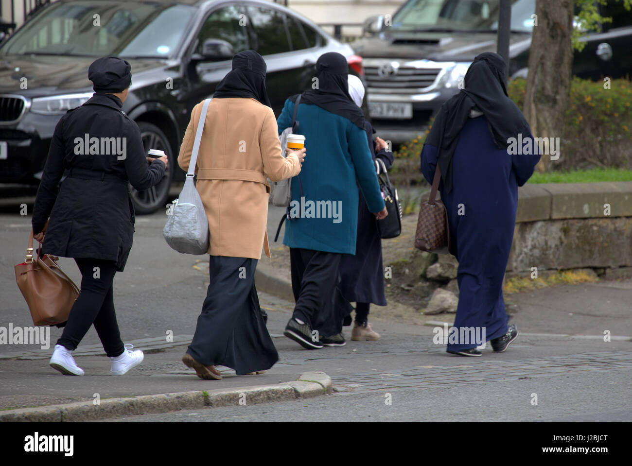 Des réfugiés africains asiatiques habillés burqa Hijab foulard sur street au Royaume-Uni scène quotidienne cinq jeunes filles marcher dans la foule de boire du café Banque D'Images