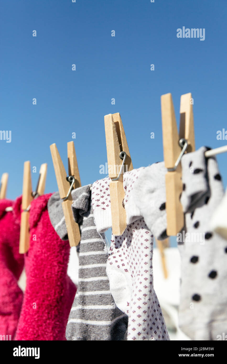 Chaussettes colorées tomber sur une ligne de lavage dans le lumineux soleil chaud. L'arrière-plan est un ciel bleu clair. Banque D'Images