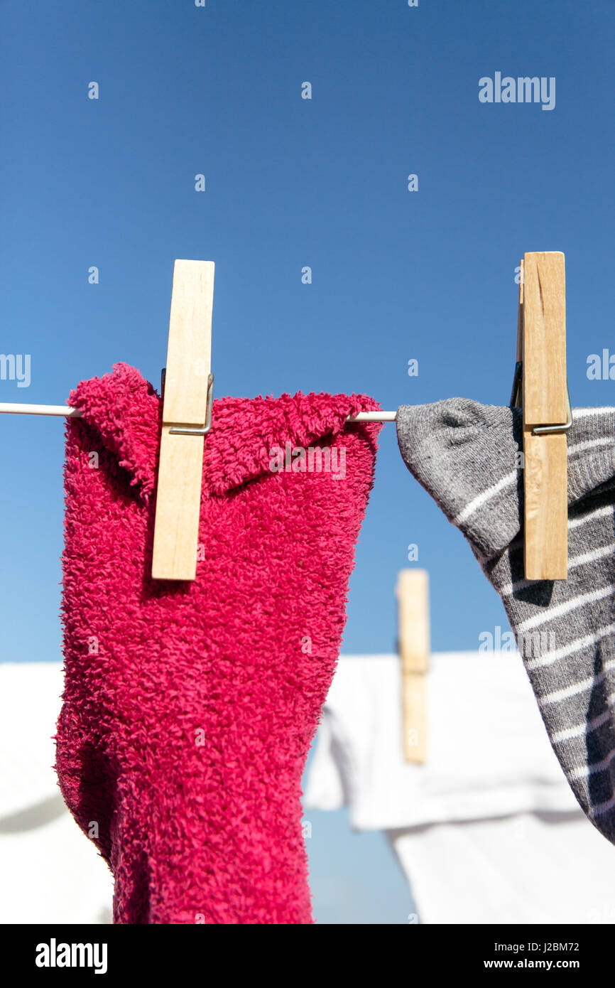 Chaussettes colorées tomber sur une ligne de lavage dans le lumineux soleil chaud. L'arrière-plan est un ciel bleu clair. Banque D'Images