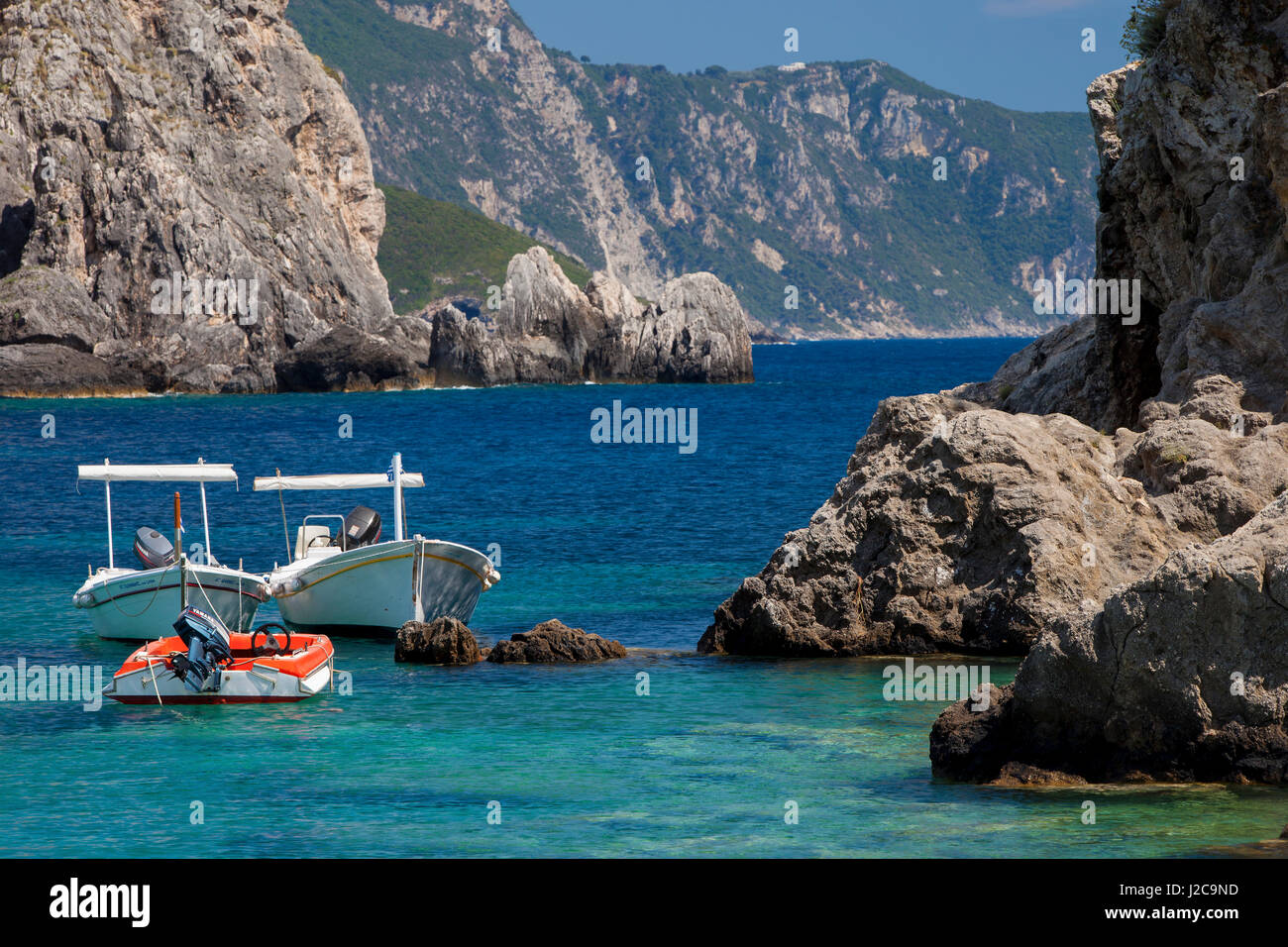 Bateaux ancrés le long de la côte grecque rocheuse près de Paleokastrita sur l'île Ionienne de Corfou, Grèce Banque D'Images