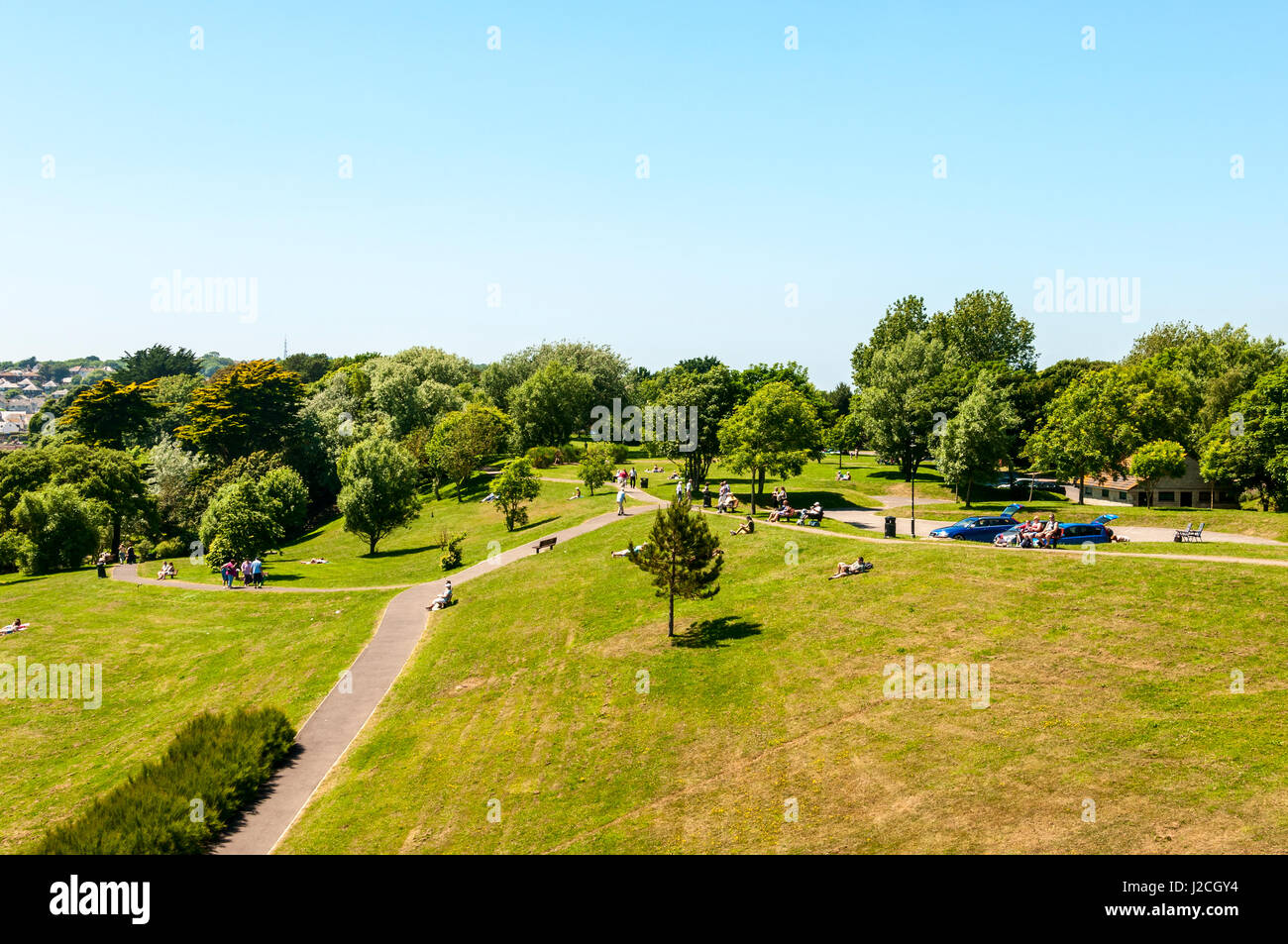 Les gens profiter de la chaleur du soleil à Réting sur les sièges ou sur l'herbe verte tondue whil plus actif de la promenade le long des voies betweenverdant feuillus Banque D'Images
