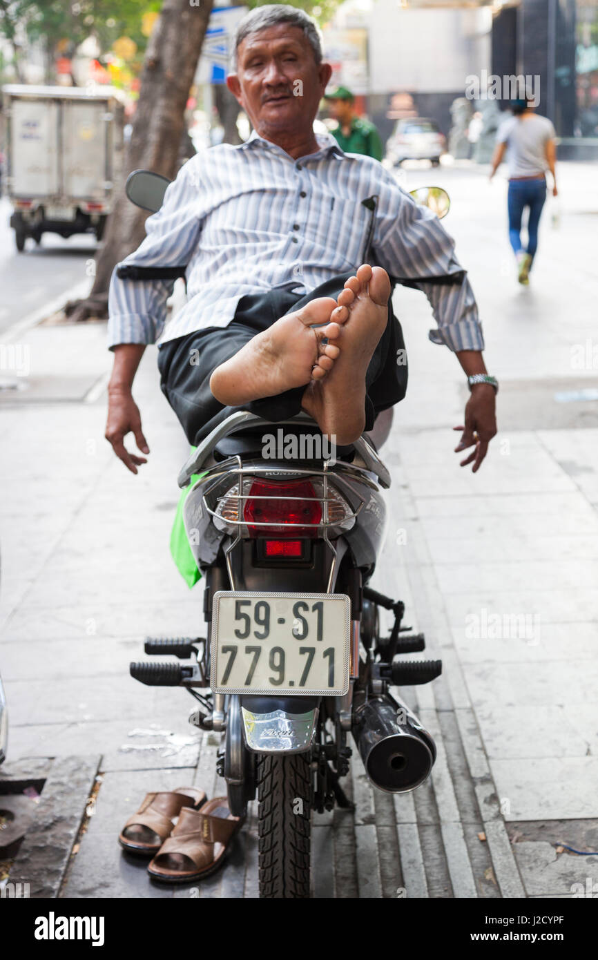 Vietnam, Ho Chi Minh Ville. L'homme se reposant sur moto Banque D'Images