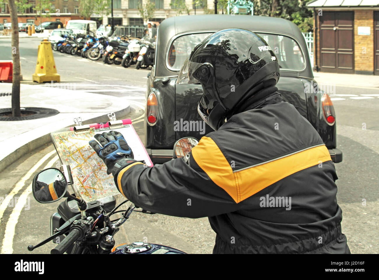 Conducteur de taxi noir stagiaire assis sur moto vérifiant les rues et les itinéraires sur la carte routière A-Z en préparation pour le test de connaissances de Londres capitale Angleterre Royaume-Uni Banque D'Images