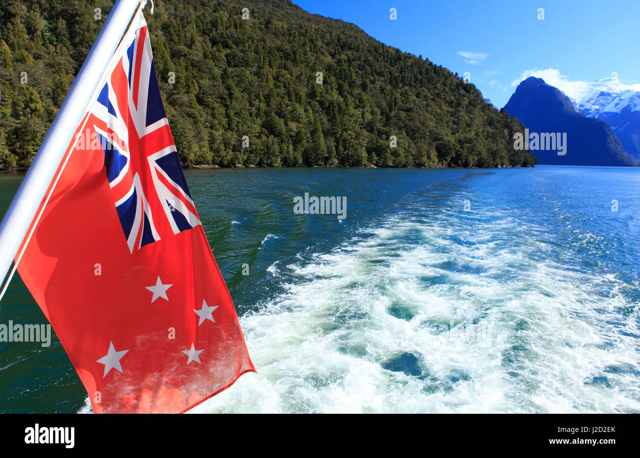 La Nouvelle Zélande drapeau flotte maritime au large de la poupe d'un bateau de croisière sur le Milford Sound, dans l'île du sud de Nouvelle-Zélande. Banque D'Images