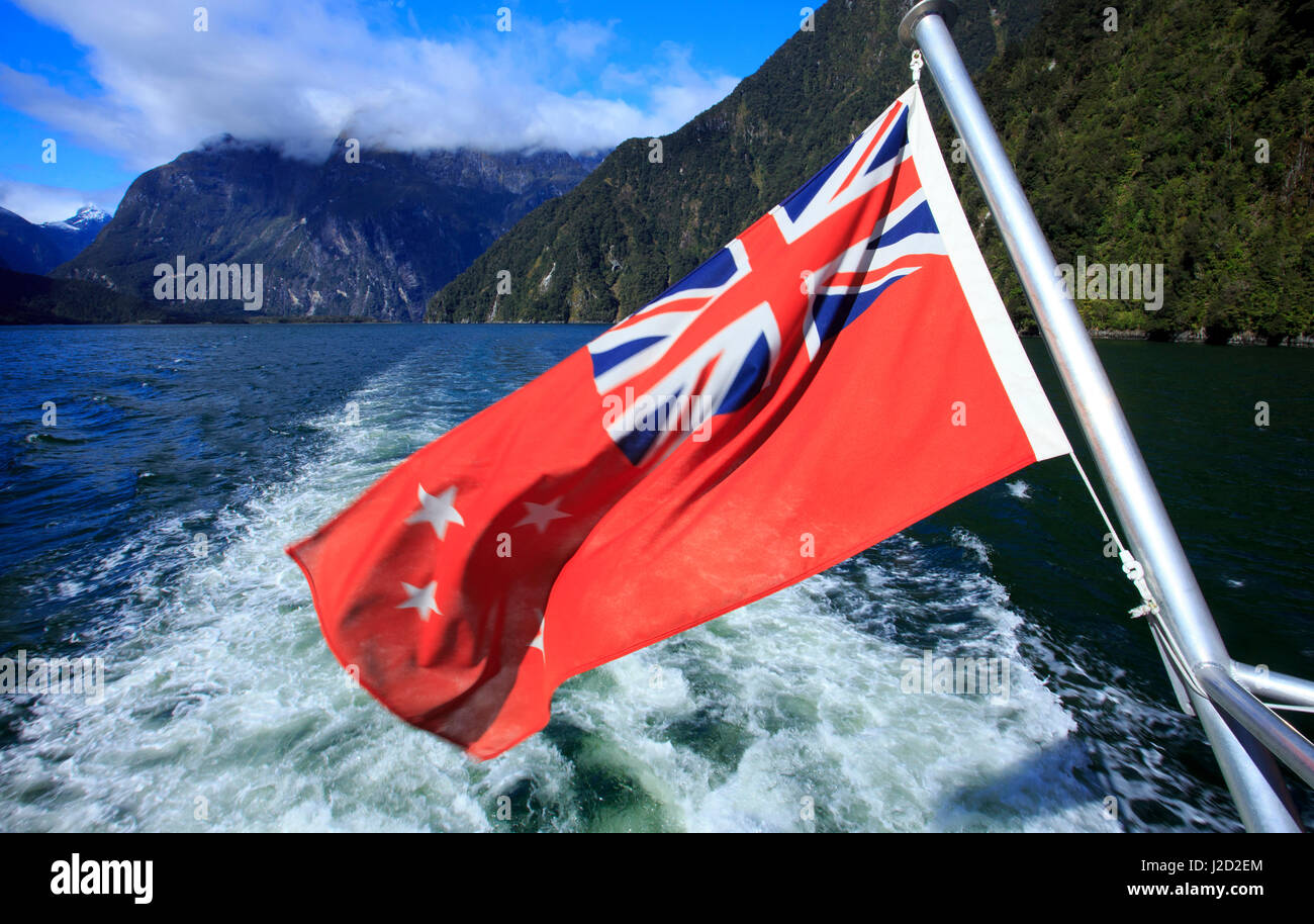 La Nouvelle Zélande drapeau flotte maritime au large de la poupe d'un bateau de croisière sur le Milford Sound, dans l'île du sud de Nouvelle-Zélande. Banque D'Images