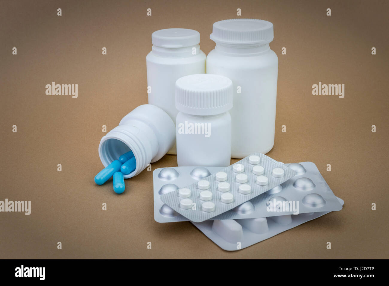 Pilules, bleu et blanc ensemble blanc plastique conteneur sur fond brun Banque D'Images