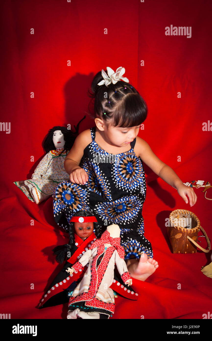 Trois ans Native American girl joue avec un assortiment de poupées traditionnelles, des jouets et des paniers. (MR) Banque D'Images