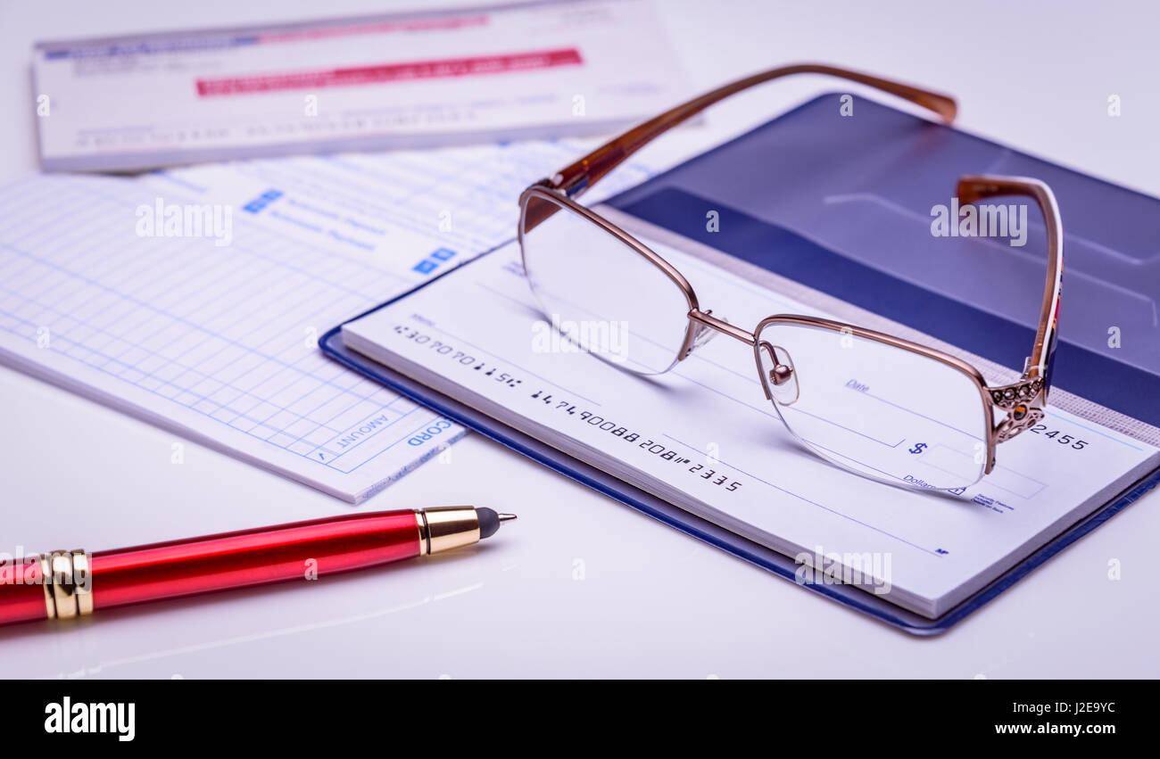 Payer avec vérifier instantanément, à l'heure. verres sur un chéquier, stylo rouge, documents financiers sur l'arrière-plan. libre, concept financier. Banque D'Images