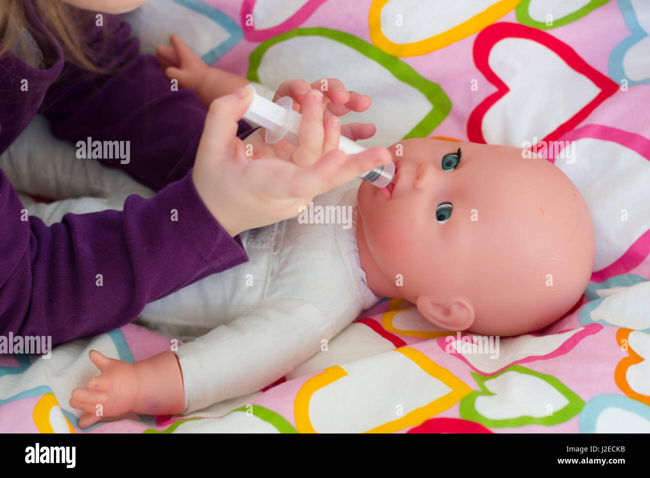 Little girl playing doctor avec une poupée et l'application de médicaments  avec seringue et en prenant soin d'une poupée, de concept et de l'enfance,  les habitudes de vie de la maternité Photo
