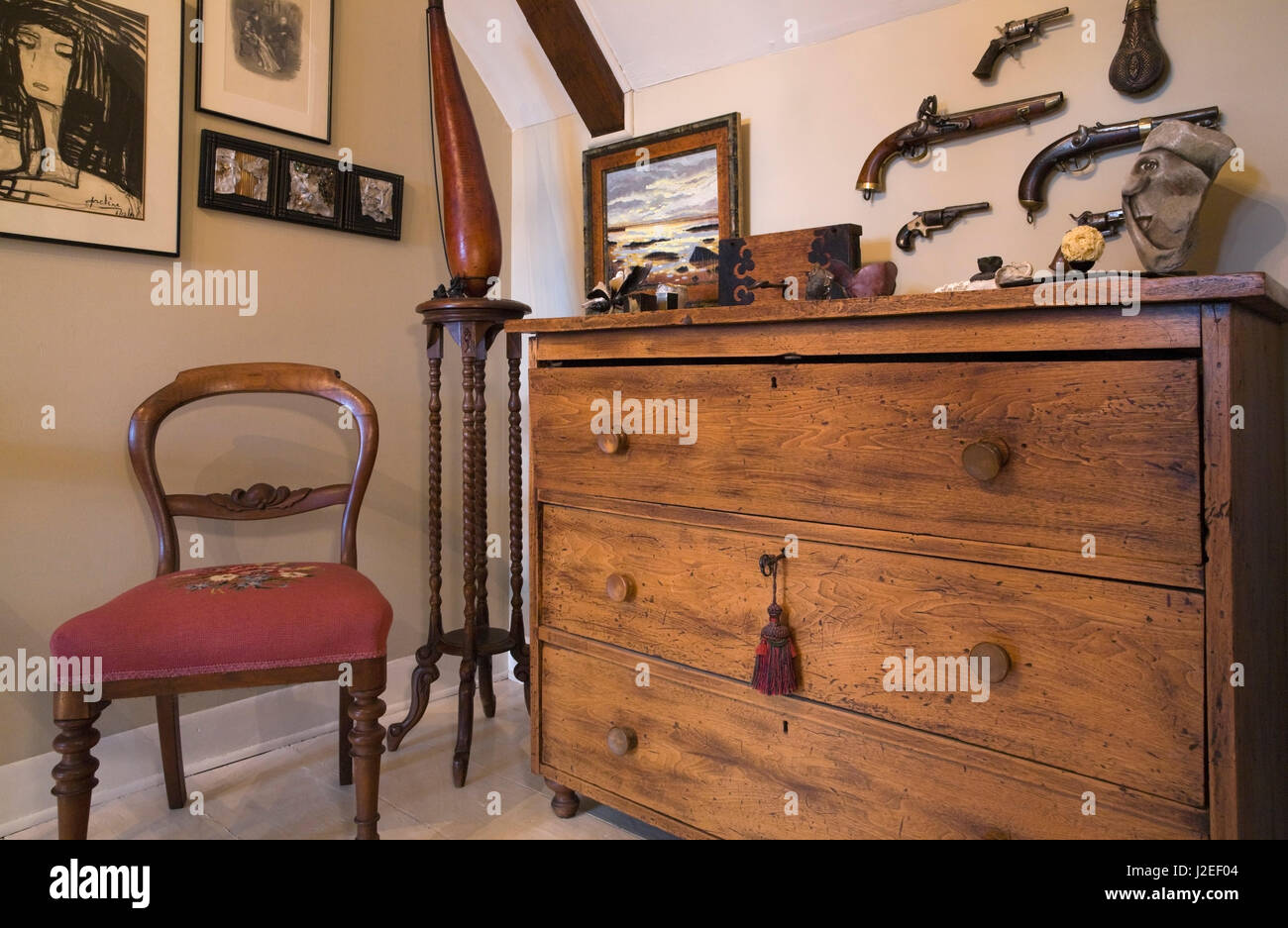 Meubles anciens en bois commode, fauteuil rouge sur l'étage couloir et des murs décorés avec des peintures et des pistolets à l'intérieur d'un vieux 1809 accueil. Banque D'Images