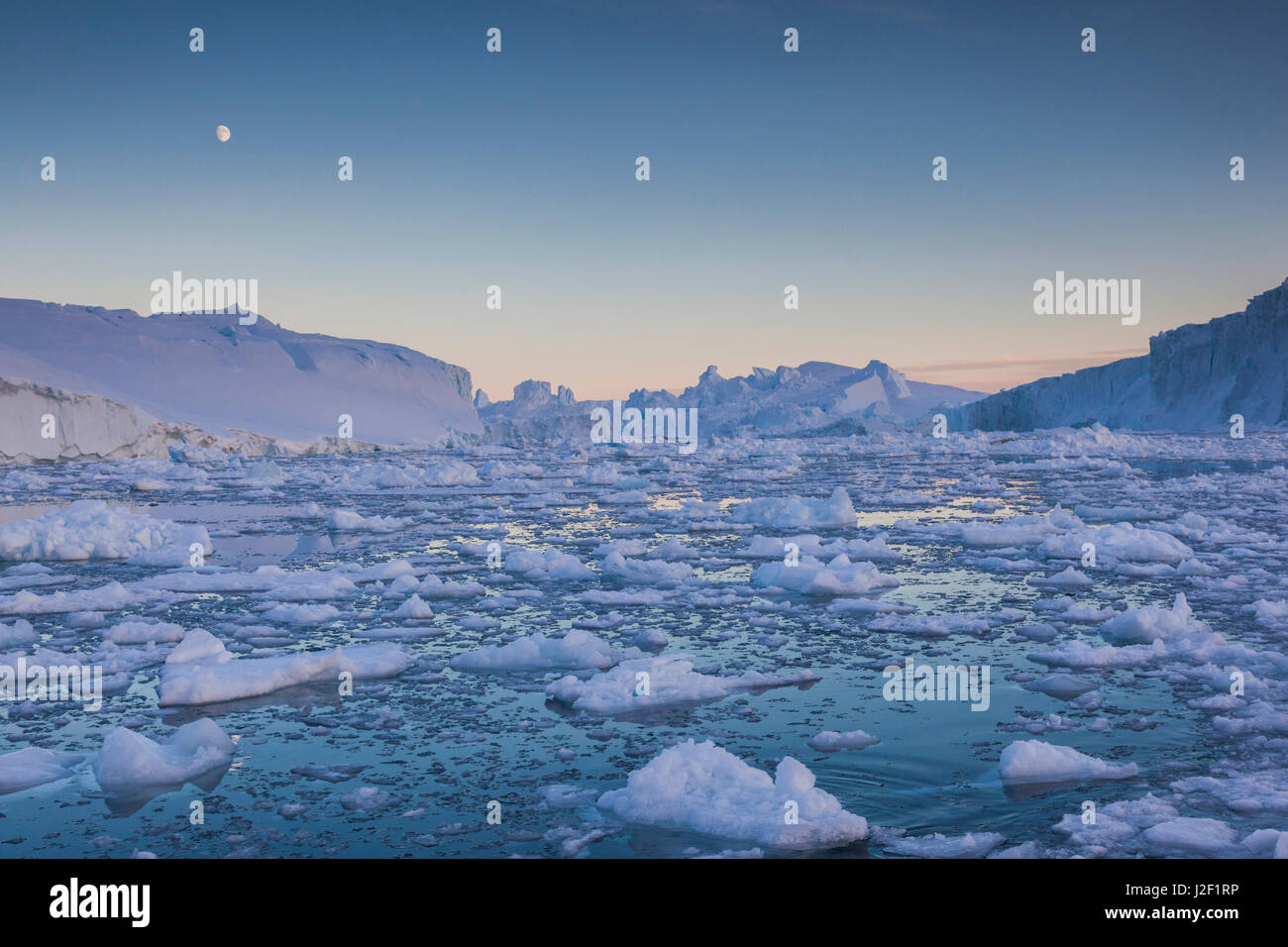 Le Groenland, baie de Disko, Ilulissat, la glace flottante au coucher du soleil avec moonrise Banque D'Images