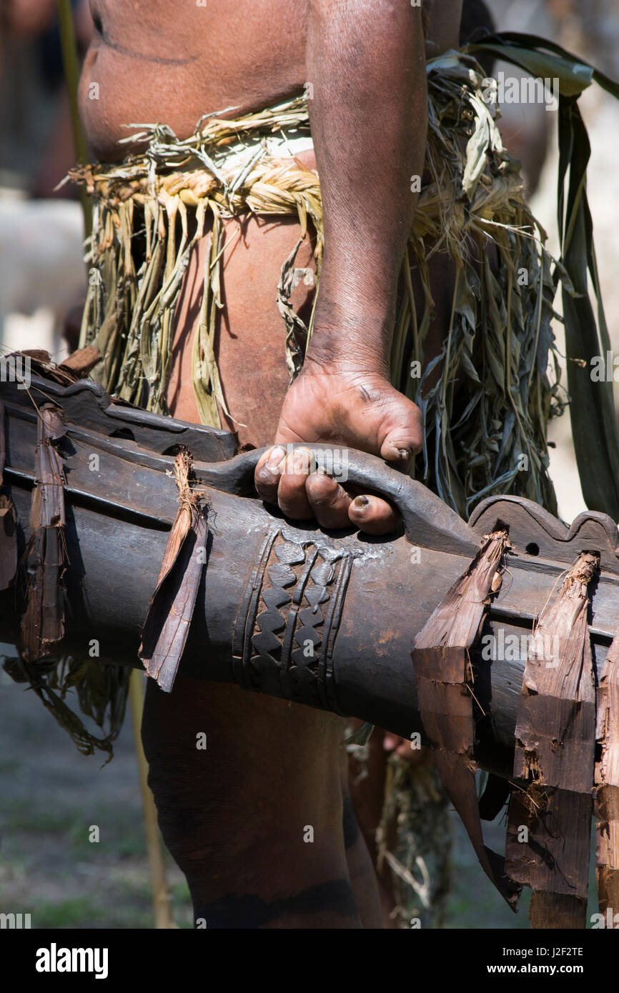 En Mélanésie, la Papouasie-Nouvelle-Guinée, l'île de dobu. détail de l'homme de village avec main blessée maintenant chanter chanter en bois traditionnel-tambour. Banque D'Images