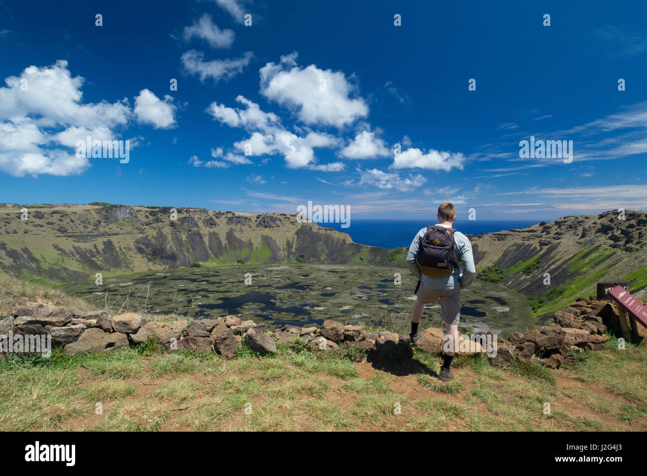 L'île de Pâques Rapa Nui, aka Orongo Rapa Nui, NP. Rano Kau, le plus grand cratère volcanique sur l'île. Randonneur sur bord du cratère surplombant fracture ou 'bite' appelée Kari Kari, lacs d'eau douce à l'intérieur. Banque D'Images