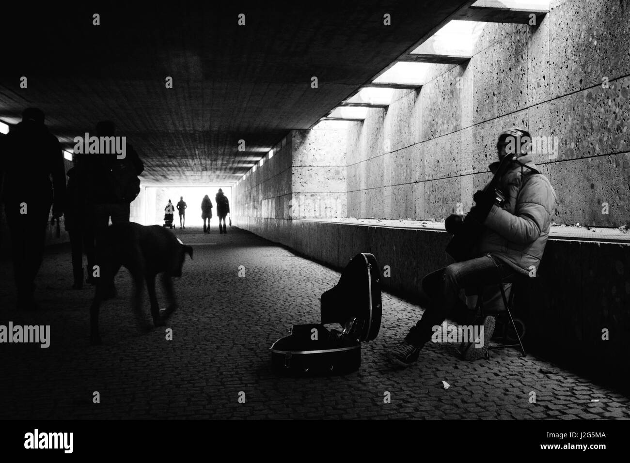 Musicien ambulant de rue/musicien jouant de la guitare pour de l'argent dans un passage souterrain pour piétons à Munich, à proximité du Jardin Anglais. Composition en noir et blanc. 5t Banque D'Images