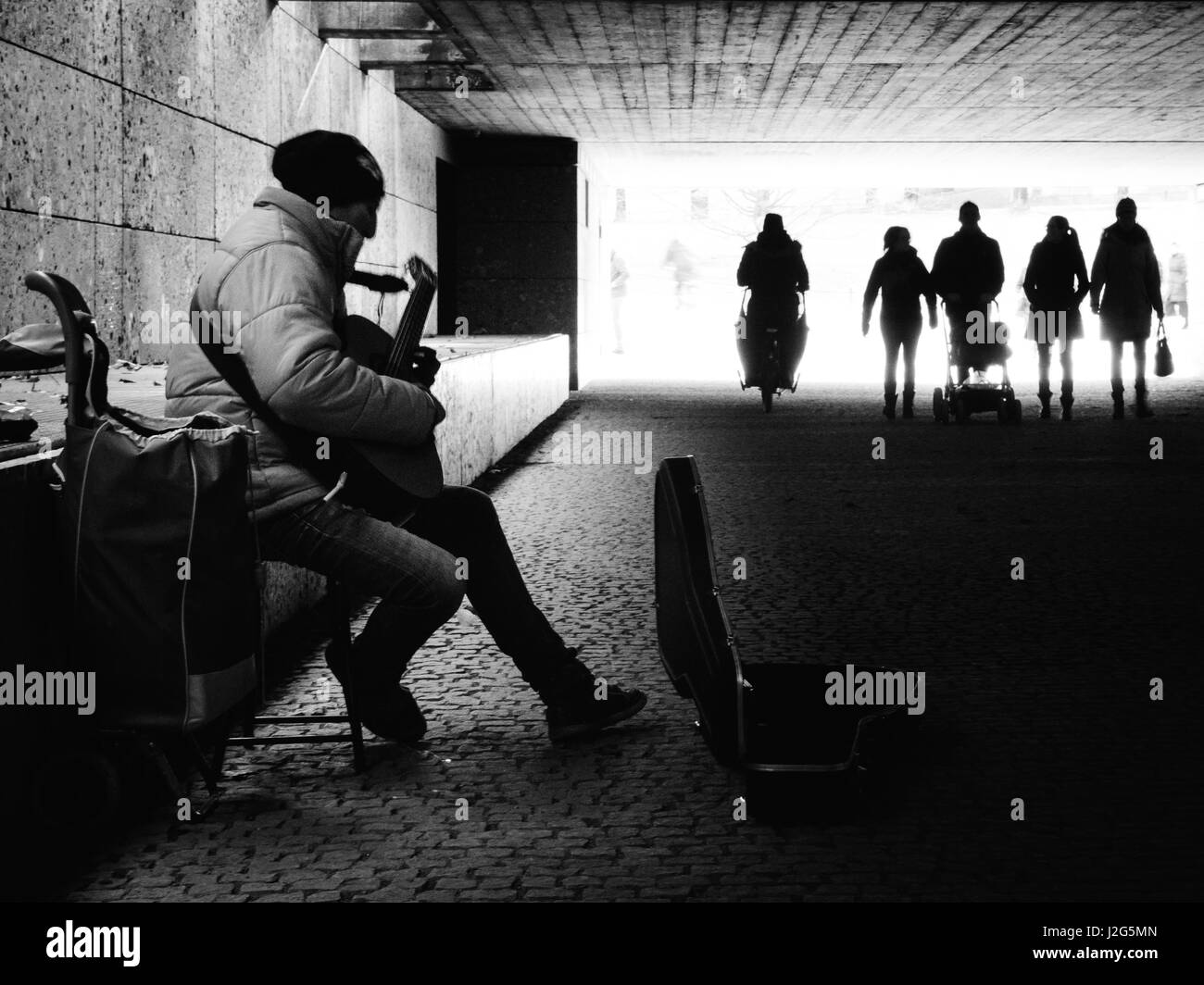 Musicien ambulant de rue/musicien jouant de la guitare pour de l'argent dans un passage souterrain pour piétons à Munich, à proximité du Jardin Anglais. Composition en noir et blanc. 5t Banque D'Images