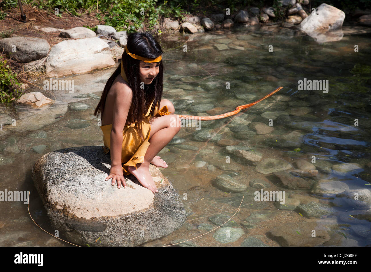 Enfant dépeint la vie des Indiens de la Mission de la Californie début jouant dans un courant d'eau peu profonde pendant que vêtus de la pré-histoire des vêtements traditionnels à Tongva Village situé dans le comté d'Orange Banque D'Images