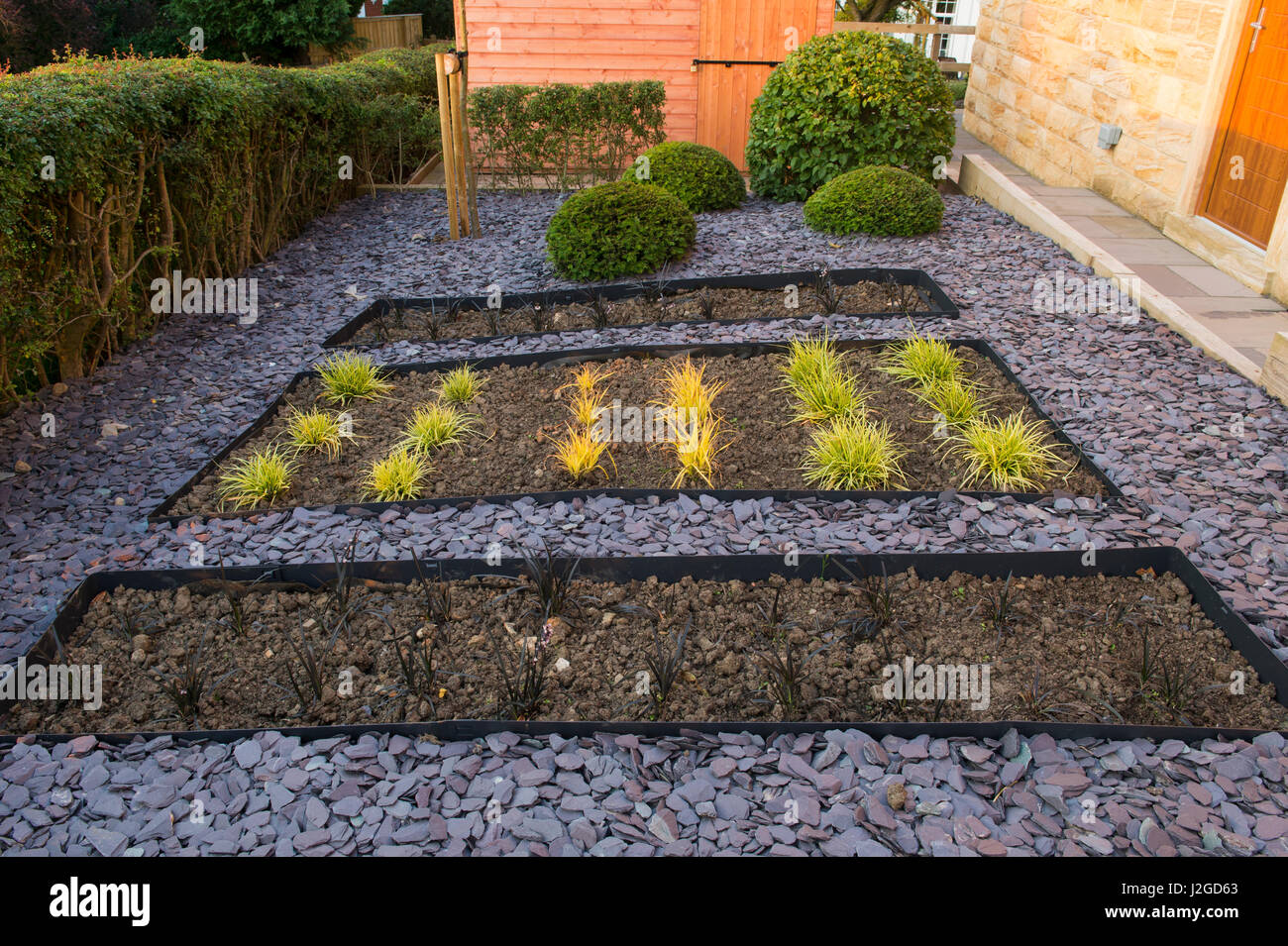 Belle, jardin privé, Aquitaine, FR, UK. Élégant et contemporain, l'aménagement paysager, la nouvelle plantation (graminées) lits en contrebas, le paillis d'ardoise, topiary et remise Banque D'Images