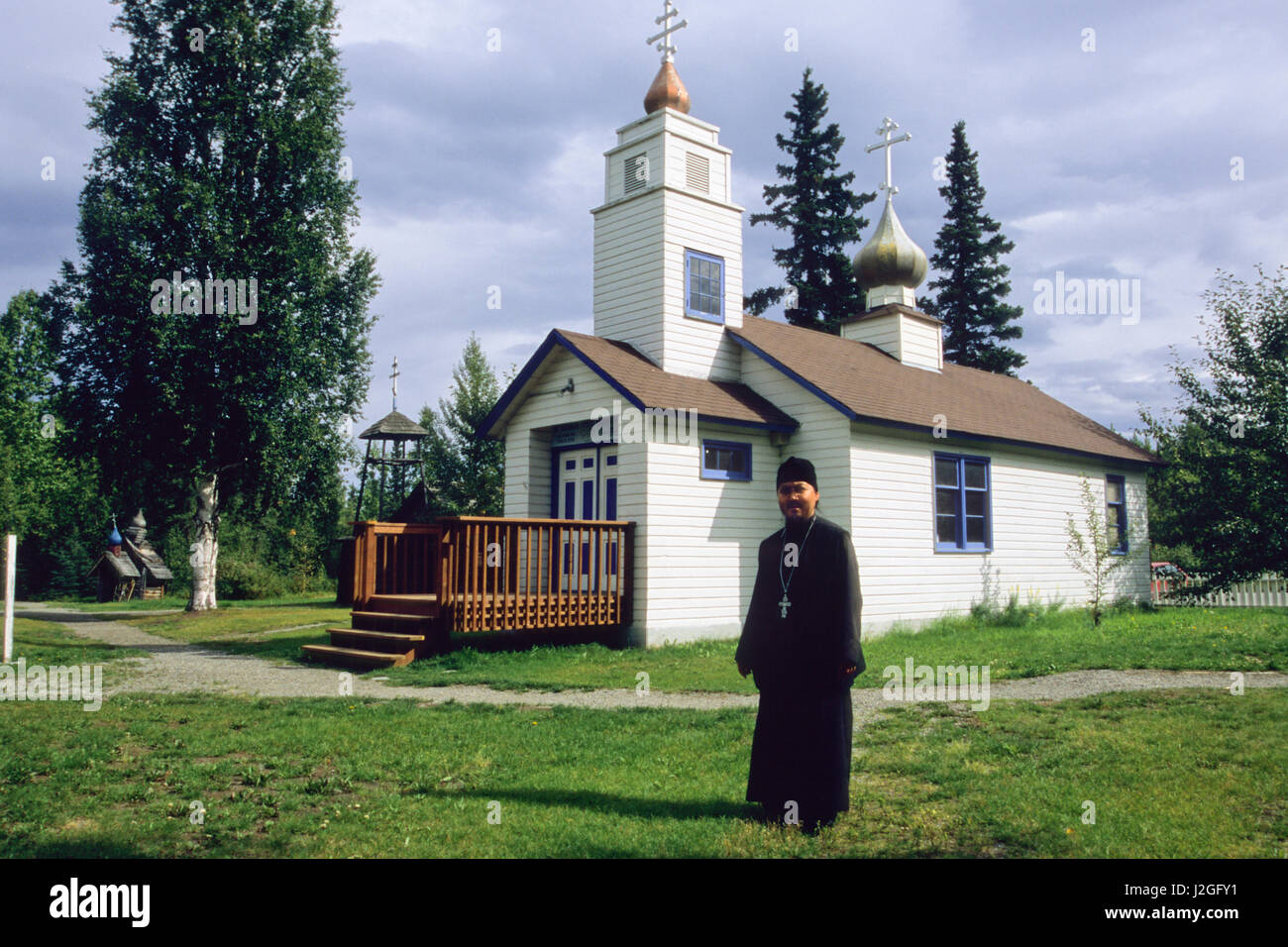 Homme d'Alaska vêtus de robes noires de la paroisse se trouve en face de l'Église orthodoxe russe Saint-nicolas à Eklutna Historical Park, situé à l'intérieur d'origine de l'Athabaskan, indiens. Eklutna Alaska Banque D'Images