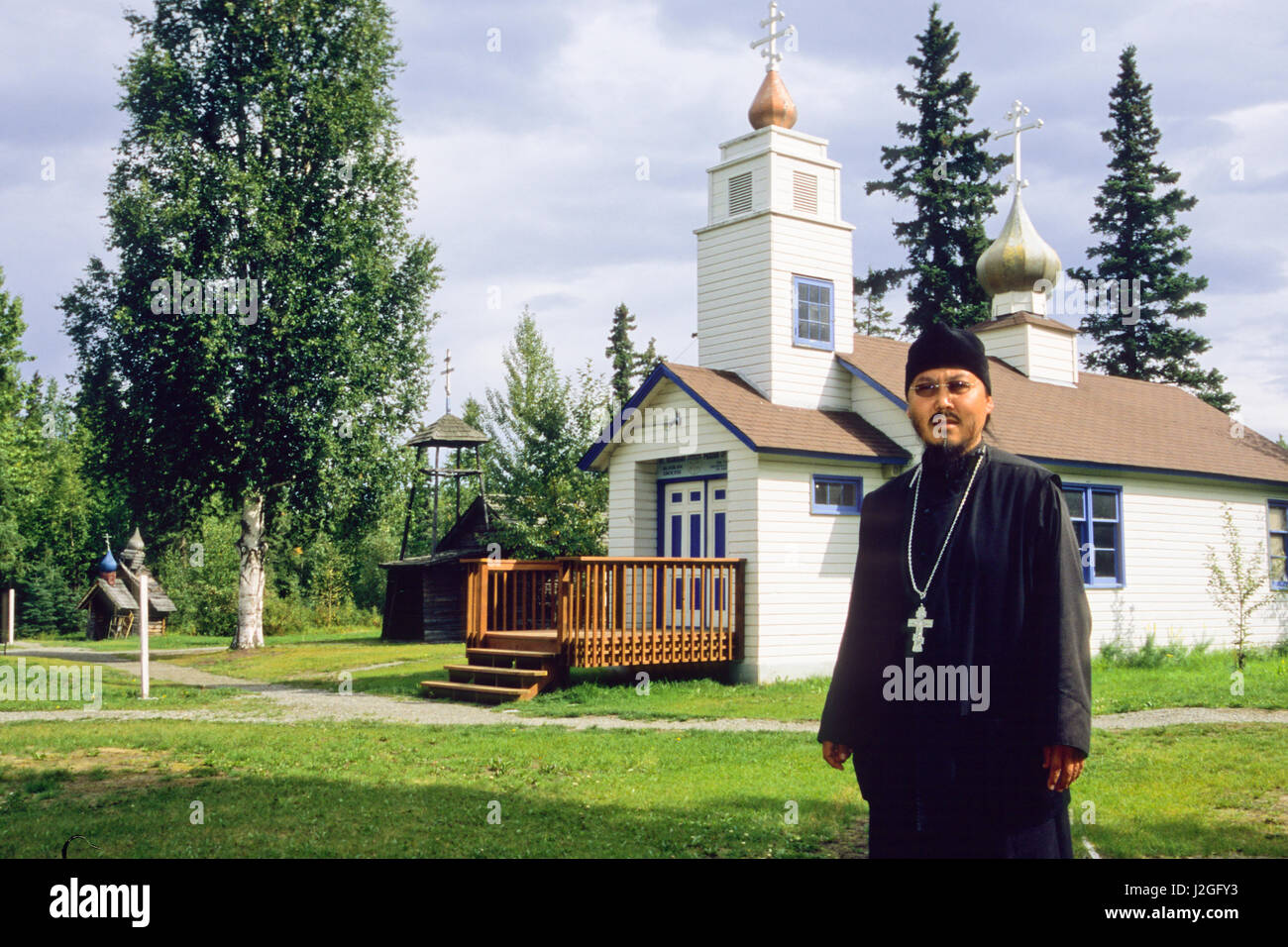 Homme d'Alaska vêtus de robes noires de la paroisse se trouve en face de l'Église orthodoxe russe Saint-nicolas à Eklutna Historical Park, situé à l'intérieur d'origine de l'Athabaskan, indiens. Eklutna Alaska Banque D'Images